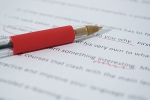 Picture of a red pen being used to correct documents after proofreading