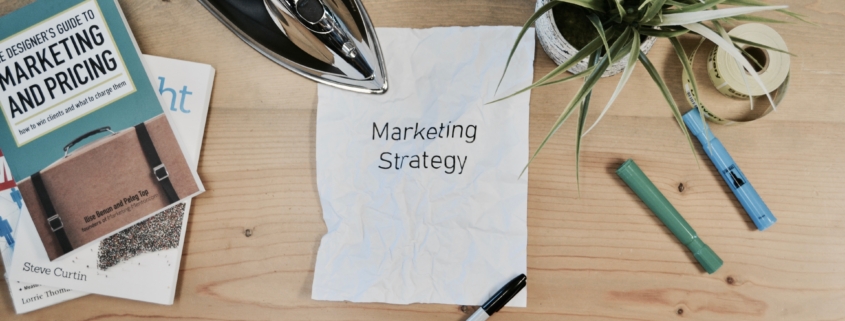 marketing strategy written on paper with textbooks and stationery surrounding it