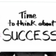 hands holding up a board with the words time to think about success on it