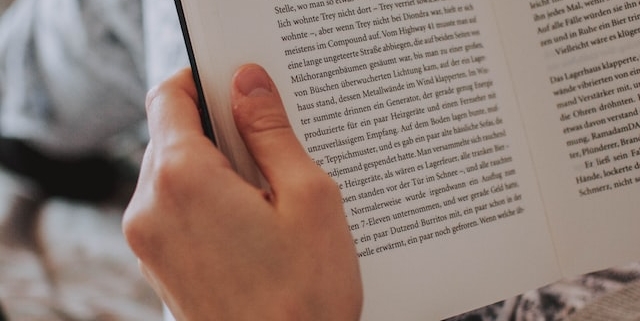 Picture of hands holding a book open as it's being read for social media marketing