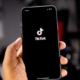 A mobile phone in someone's hand with the Tiktok loading screen