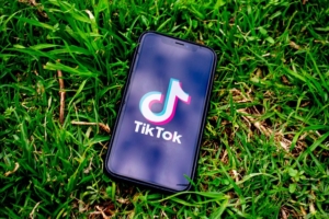 a mobile phone lying on green grass with the tiktok app open